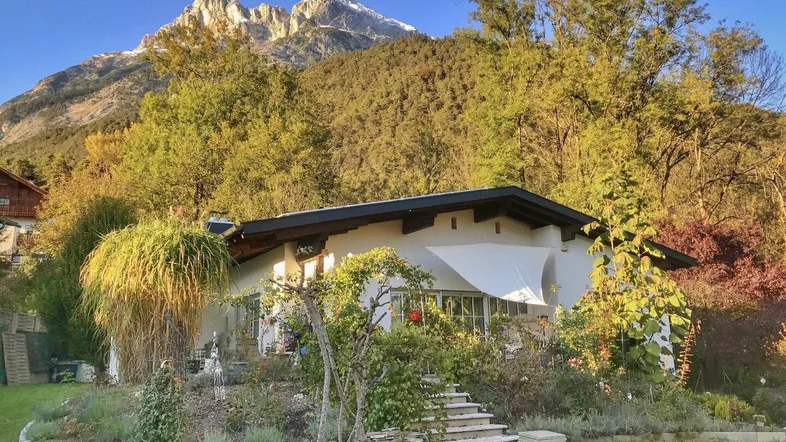 Charmantes Haus mit weißer Fassade, umgeben von einem gepflegten Garten und mit herrlichem Bergblick.