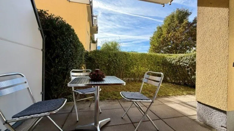 Gepflasterte Terrasse mit Gartenmöbeln und Hecke, ideal für entspannte Stunden im Freien.