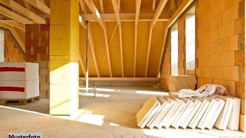 Unfertiger Dachboden im Rohbau mit sichtbaren Holzbalken und Baumaterialien, bereit für den Ausbau.