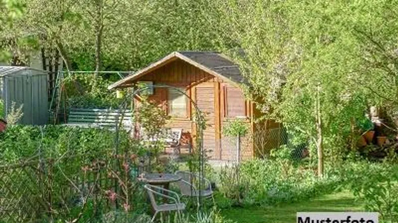 Kleiner Holzschuppen in einem grünen Garten mit Sitzgelegenheiten und üppiger Vegetation.