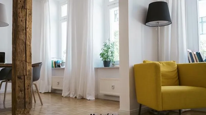 Helles Wohnzimmer mit Holzbalken, gelbem Sessel und großen Fenstern mit weißen Vorhängen.