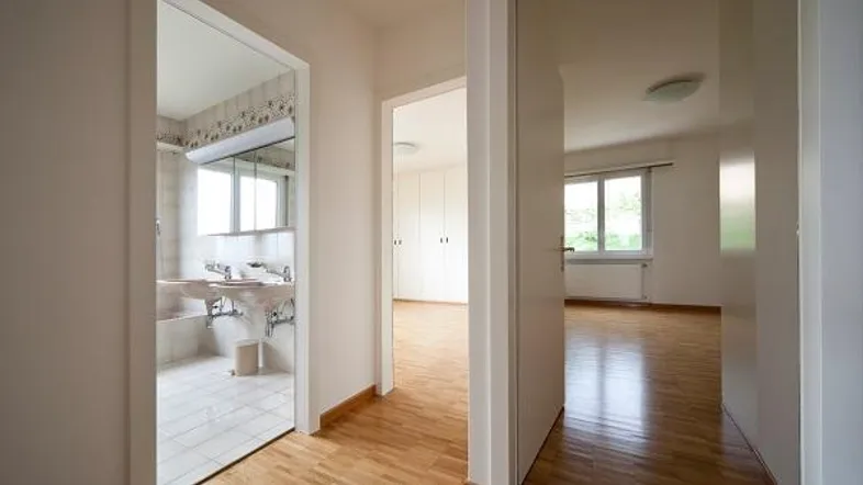 Heller Flur mit Parkettboden und Zugang zu einem Badezimmer sowie einem weiteren Zimmer.