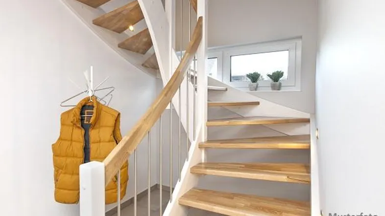 Helle Holztreppe mit weißem Geländer und einem Fenster, das natürliches Licht hereinlässt.