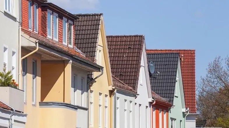 Reihe bunter Wohnhäuser mit Satteldächern und Gauben unter blauem Himmel.