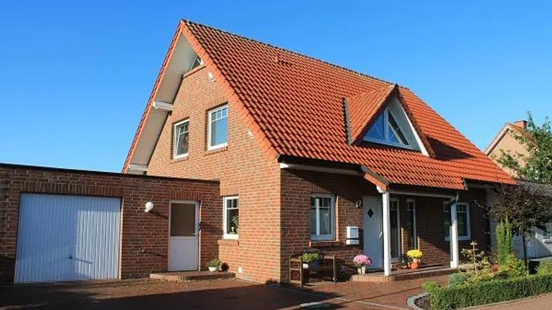 Einfamilienhaus aus rotem Backstein mit rotem Ziegeldach und integrierter Garage.