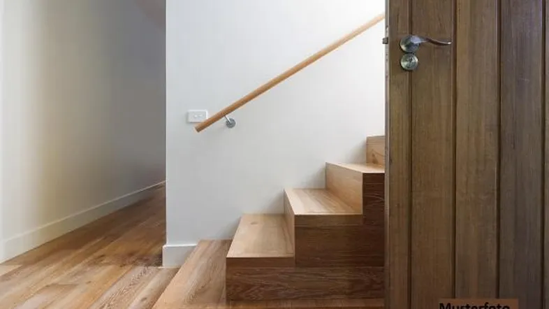 Moderne Holztreppe mit hellem Handlauf und passender Holztür in einem lichtdurchfluteten Flur.