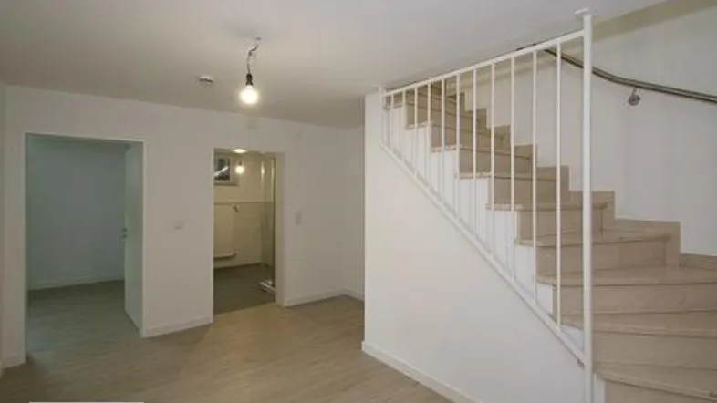 Heller Flurbereich mit Holzoptikboden und einer Treppe, die in die obere Etage führt.