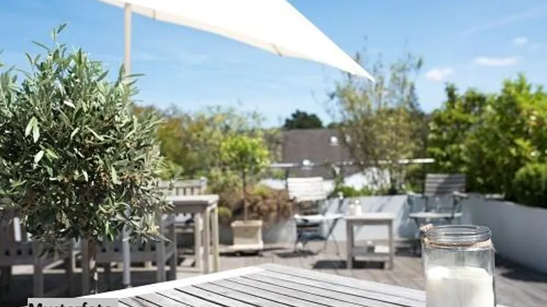 Sonnige Terrasse mit Holztisch, Sonnenschirm und Pflanzen, ideal für entspannte Stunden im Freien.