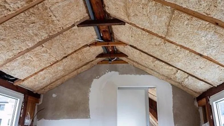Dachgeschossraum im Rohbau mit sichtbarer Dämmung und Holzkonstruktion, bereit für den Ausbau.