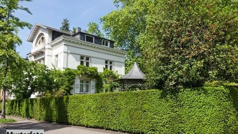 Klassische weiße Villa mit gepflegter Hecke und üppiger Begrünung in sonniger Umgebung.