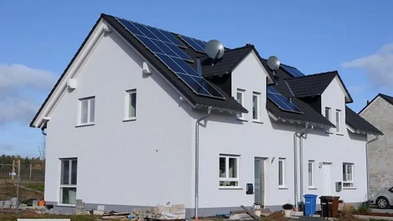 Modernes Einfamilienhaus mit Solaranlage auf dem Dach und Gaubenfenstern unter blauem Himmel.