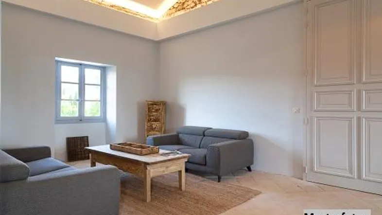 Helles Wohnzimmer mit modernen Sofas, Steinfußboden und einer dekorativen Deckenbeleuchtung.