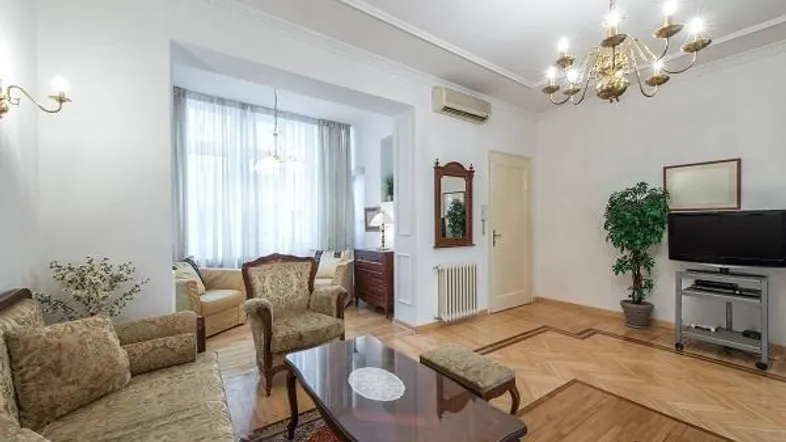 Klassisch eingerichtetes Wohnzimmer mit Parkettboden, Stuckdecke und einem eleganten Kronleuchter.