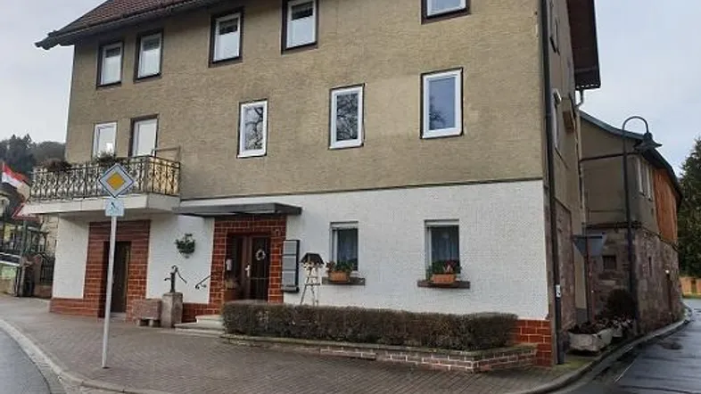 Mehrstöckiges Gebäude mit Balkon und gemischter Fassade an einer Straßenecke.
