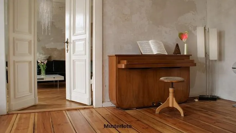 Heller Raum mit Holzdielenboden und einem Klavier, offene Tür zu einem weiteren Wohnbereich.