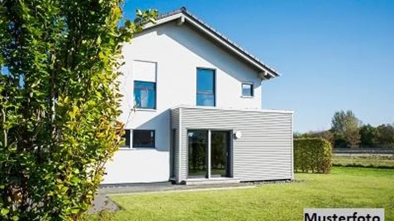 Modernes Einfamilienhaus mit weißer Fassade, großen Fenstern und gepflegtem Rasen unter blauem Himmel.