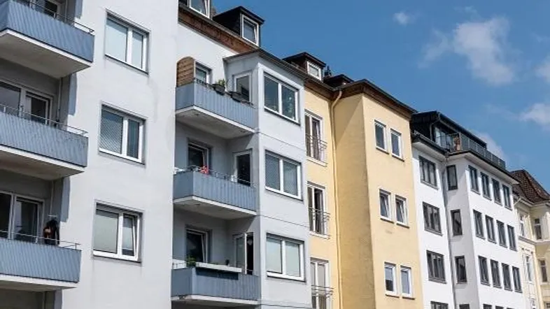 Reihe von Mehrfamilienhäusern mit unterschiedlichen Fassadenfarben und Balkonen unter blauem Himmel.