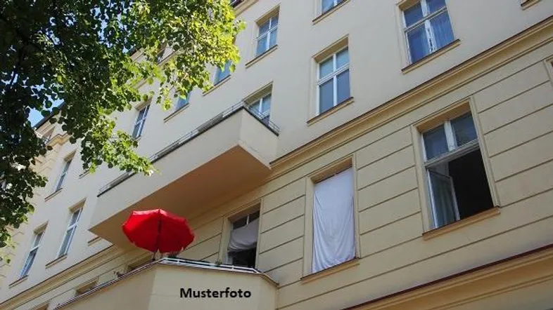 Gebäudefassade mit vielen Fenstern und einem kleinen Balkon, der mit einem roten Sonnenschirm ausgestattet ist.