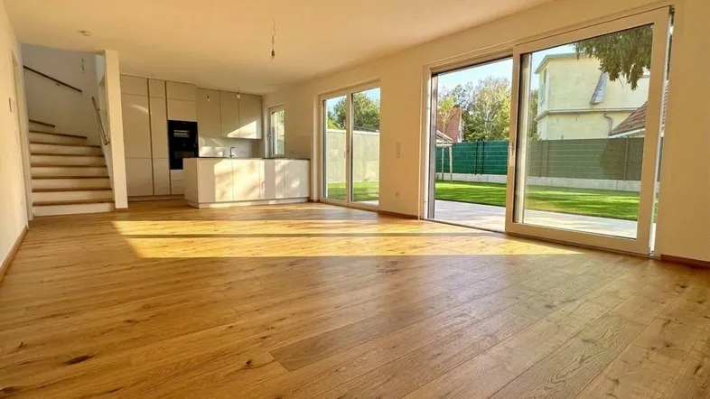 Heller offener Wohn- und Küchenbereich mit Holzboden und Zugang zum Garten.