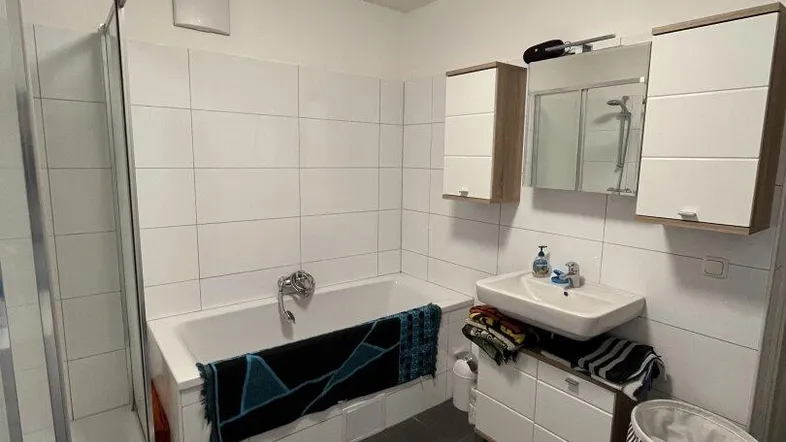 Funktionales Badezimmer mit Badewanne, Duschkabine, Waschbecken und Spiegelschrank.