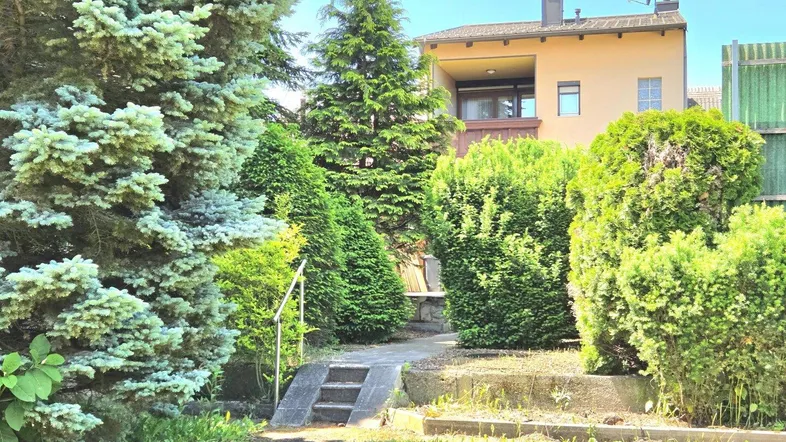 Gepflegter Gartenbereich mit üppiger Bepflanzung und Blick auf das Wohnhaus.