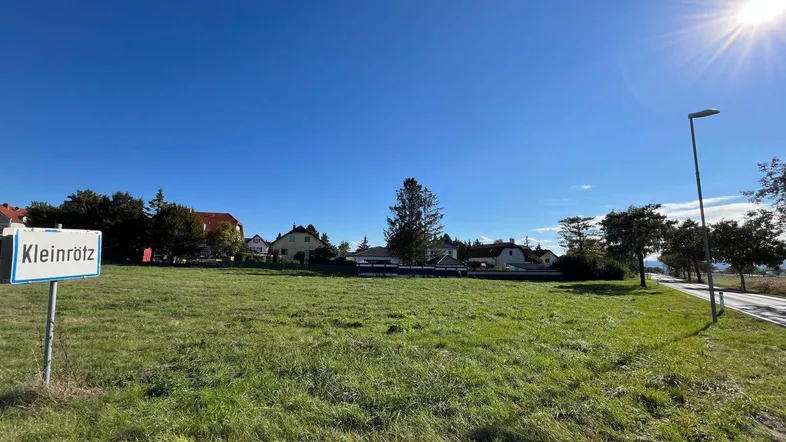 Weitläufiges grünes Grundstück unter strahlend blauem Himmel mit Blick auf die umliegende Wohnbebauung.
