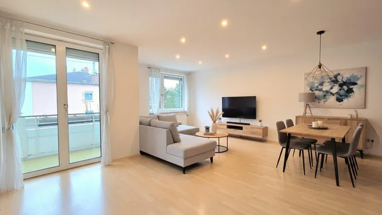 Helles, modern eingerichtetes Wohn- und Esszimmer mit Parkettboden und Zugang zum Balkon.