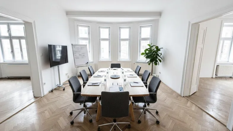 Ein modern eingerichteter Konferenzraum mit großem Holztisch, bequemen Stühlen und viel Tageslicht durch die Erkerfenster.