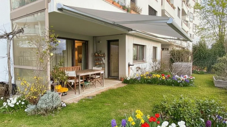 Gepflegter Garten mit blühenden Blumen, einer möblierten Terrasse und einer ausfahrbaren Markise.