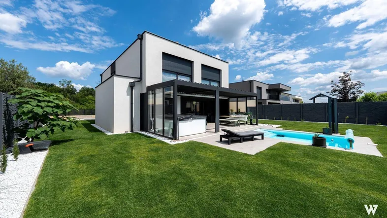 Großzügiger Gartenbereich mit modernem Pool, überdachter Terrasse und gepflegter Rasenfläche hinter dem Haus.