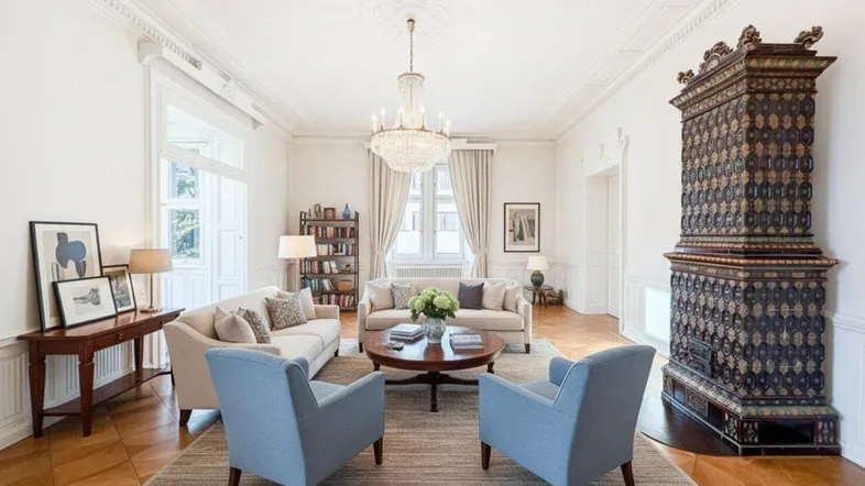 Elegantes Wohnzimmer mit Fischgrätparkett, Stuckdecke und einem traditionellen Kachelofen.