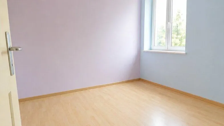 Helles, leeres Zimmer mit hellblauen und lila Wänden sowie einem Laminatboden.