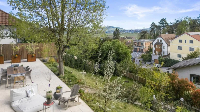 Großzügige Terrasse mit Essbereich und Lounge-Möbeln, umgeben von viel Grün und Fernblick.