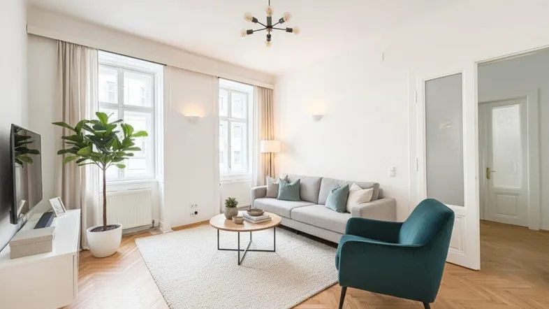 Helles Wohnzimmer mit Fischgrätparkett, modernem Sofa und einem blauen Sessel.