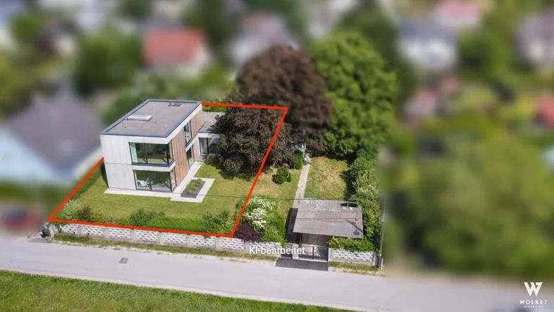 Luftaufnahme eines modernen Hauses mit großen Fenstern und einem umgrenzten Grundstück.