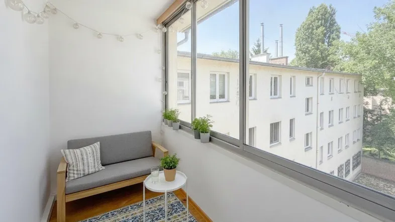 Gemütliche verglaste Loggia mit Sitzbereich und Blick auf die Umgebung.