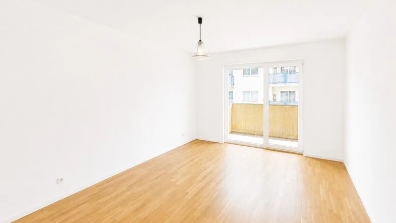Helles Wohnzimmer mit Parkettboden und Zugang zu einem Balkon, ideal für entspannte Stunden.