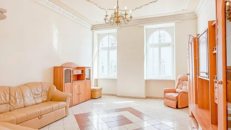 Helles Wohnzimmer mit hohen Decken, Stuckverzierungen und traditionellen Möbeln in einem Altbau.