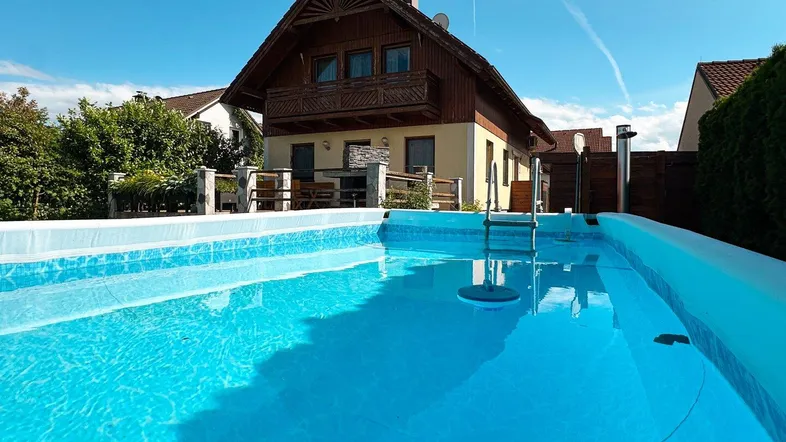 Außenpool mit klarem Wasser und Blick auf das charmante Einfamilienhaus.