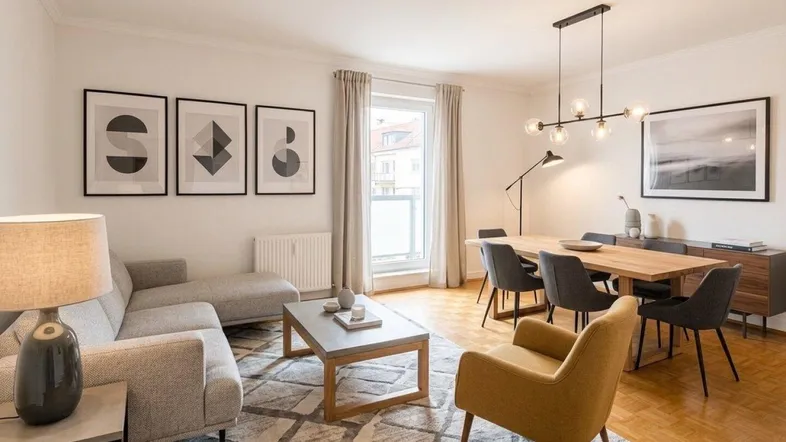 Helles Wohn- und Esszimmer mit modernem Design, Parkettboden und Zugang zum Balkon.