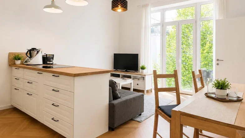 Heller offener Wohn-Essbereich mit integrierter Küche, Holzboden und großen Fenstern zum Garten.