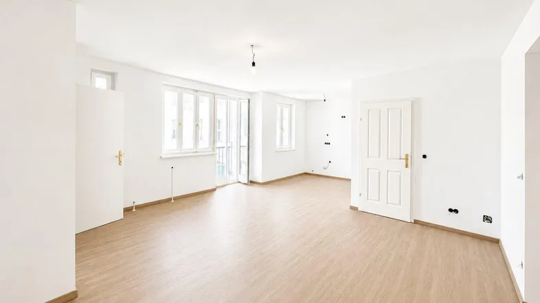 Helles, geräumiges Wohnzimmer mit neuem Bodenbelag und Zugang zu einem Balkon.