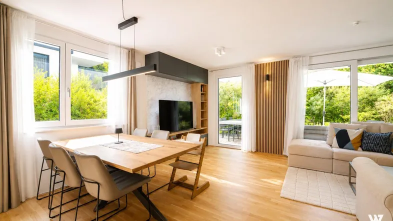 Heller, offener Wohn-Essbereich mit Holzboden, modernen Möbeln und Zugang zur Terrasse.