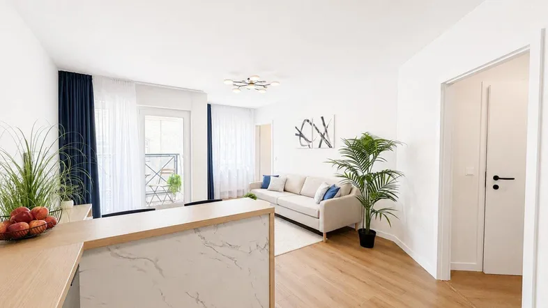 Helles Wohnzimmer mit Holzboden, Sofa und Zugang zu einem Balkon, modern eingerichtet.