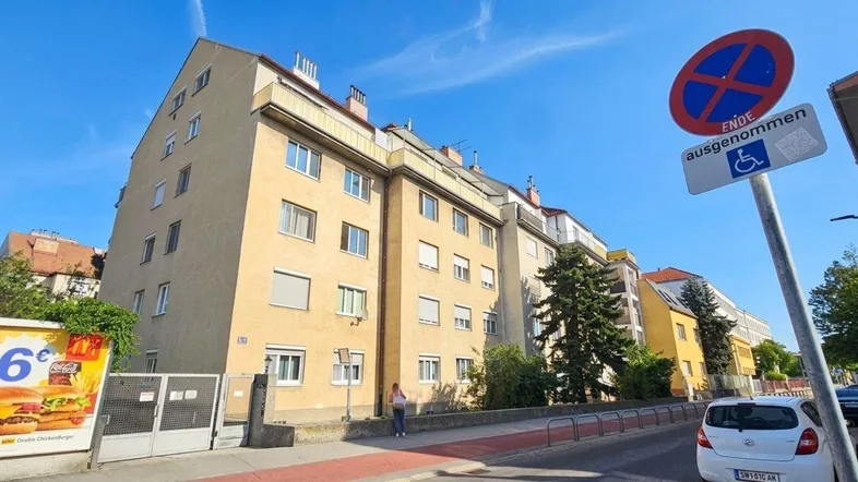 Mehrstöckiges Wohngebäude mit klassischer Fassade und Fenstern zur Straße.
