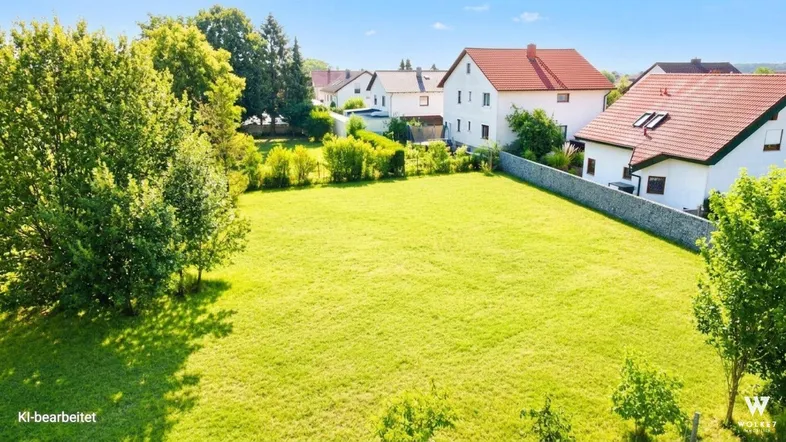 Luftaufnahme eines grünen Baugrundstücks in ländlicher Umgebung mit angrenzenden Wohnhäusern.