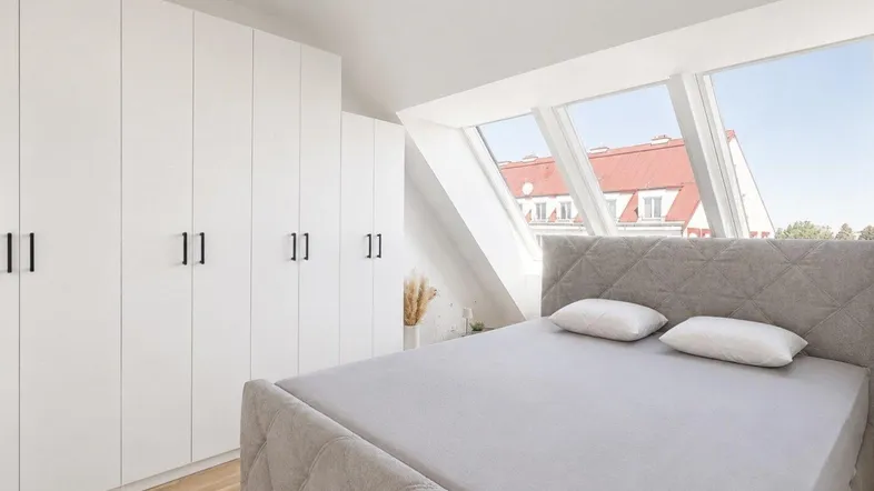 Helles Schlafzimmer im Dachgeschoss mit großen Dachfenstern und integrierten Kleiderschränken.
