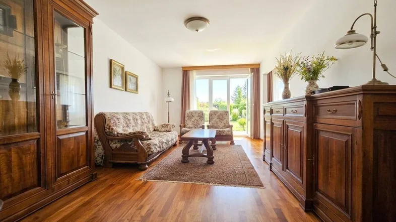 Geräumiges Wohnzimmer mit Holzboden, traditionellen Möbeln und Zugang zu einem Balkon oder Garten.
