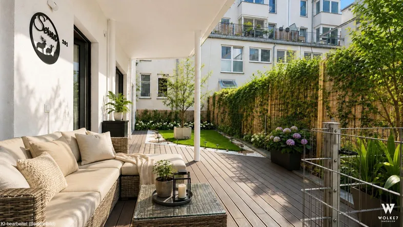 Geräumige Terrasse mit bequemen Outdoor-Möbeln, umgeben von Grünflächen und einem Bambuszaun.