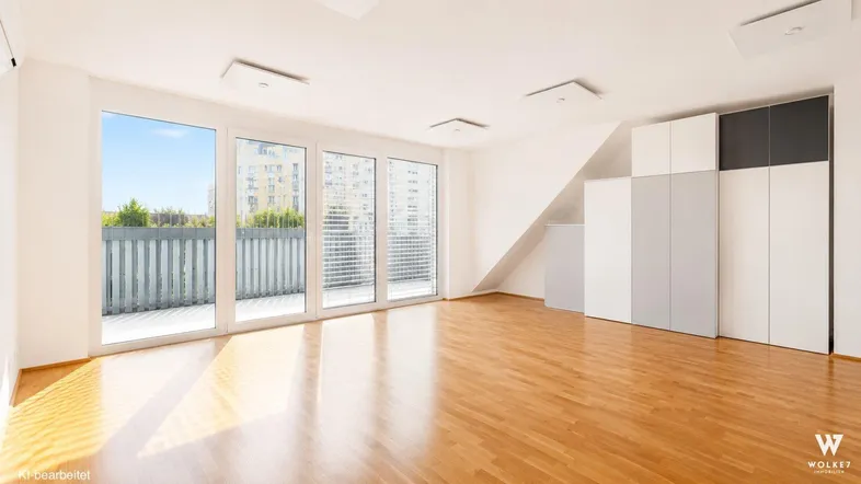 Helles Zimmer mit Holzboden, großen Fenstern zum Balkon und integrierten Schränken.